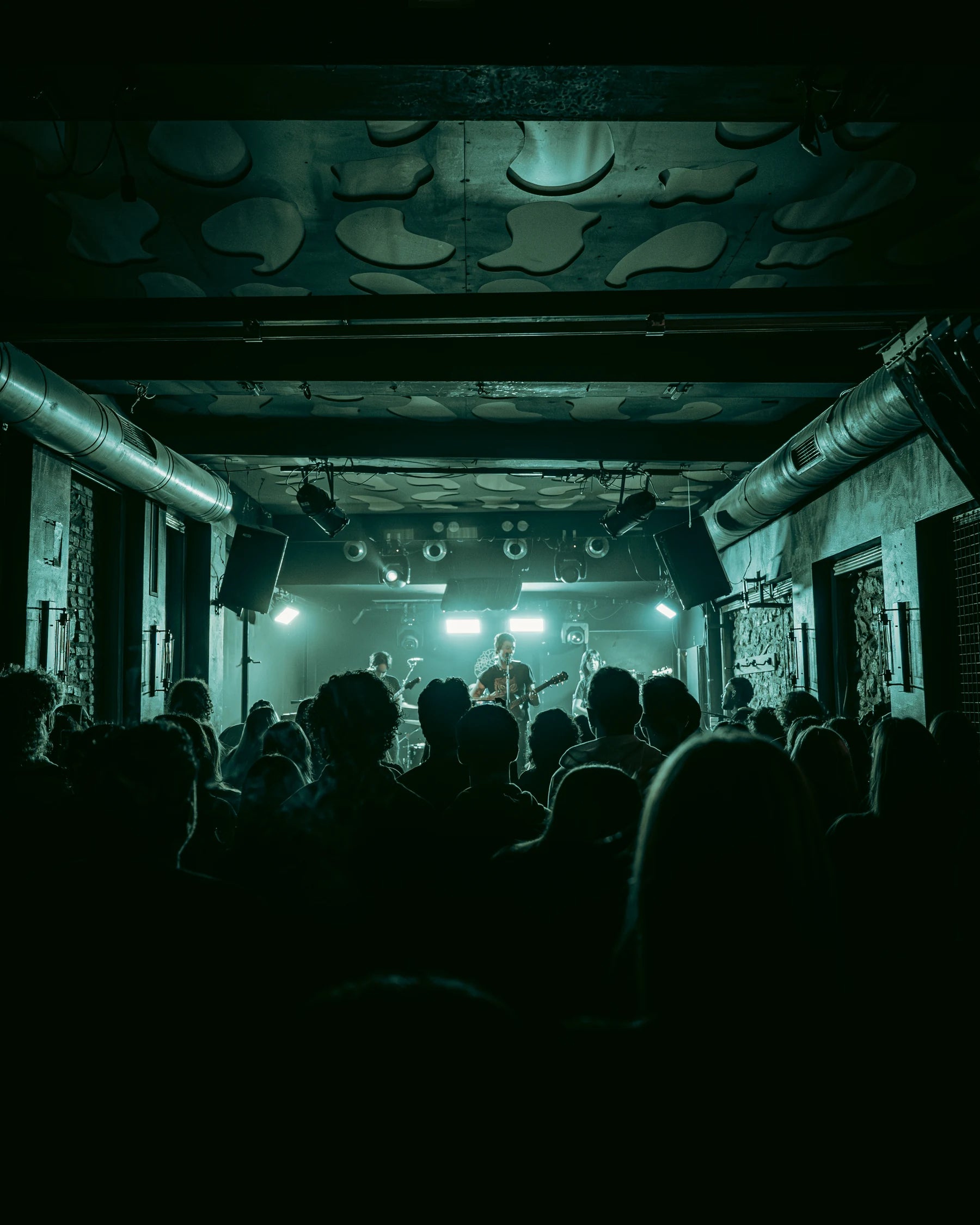 D3LTA performing at Frida in Patras on 11 March 2026, seen through the audience under green stage lights.